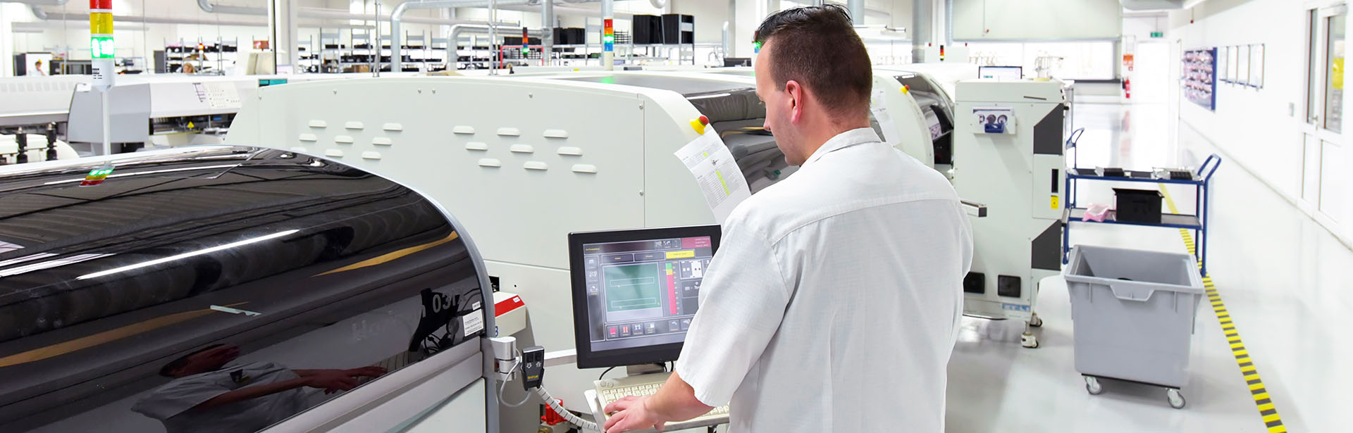 In einer hellen Fabrikhalle steuert ein Mitarbeiter eine Maschine, um den Produktionsprozess zu überwachen.