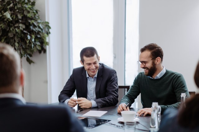 Zwei Männer lachen bei einem Meeting